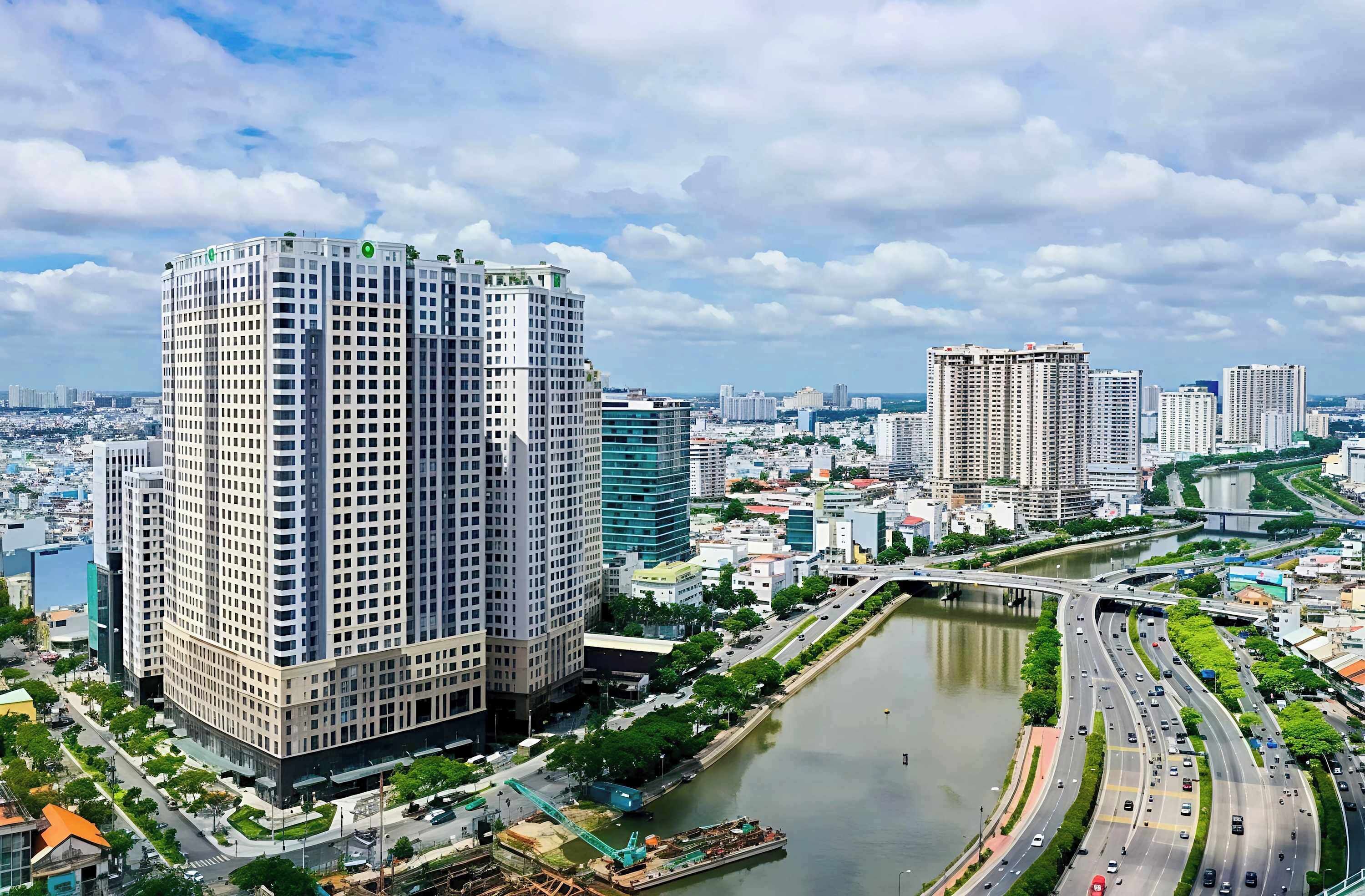 A high-rise building with a modern architectural design, surrounded by a river and a busy highway.