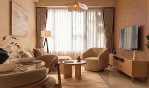 Ein modernes Wohnzimmer mit Sofa, Sessel, Couchtisch und einem Fernseher auf einer Holzkommode.