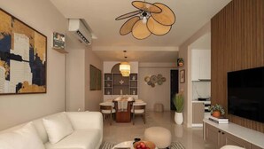 Ein modernes Wohnzimmer mit einer Couch, einem Couchtisch, einem Essbereich mit Tisch und Stühlen sowie einem Fernseher auf einem Schrank.