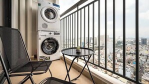 Ein Balkon mit Waschmaschine, einem Stuhl und einem Tisch mit einer Pflanze.