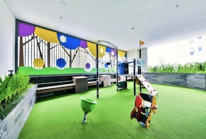 A children's play area with artificial turf, a climbing structure, and a colorful mural. - Large 3BRs+2WCs | City & D1 View | 5 min BuiVien (Thành phố Hồ Chí Minh)