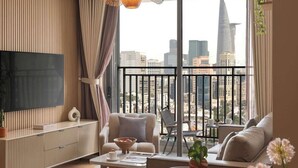 Un soggiorno moderno con un'ampia televisione, sedute confortevoli, un tavolino da caffè e vista sulla città attraverso ampie finestre.