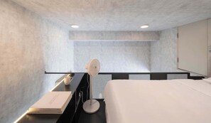 Ein modernes Hotelzimmer mit Bett, Nachttisch, Lampe und einem Buch.