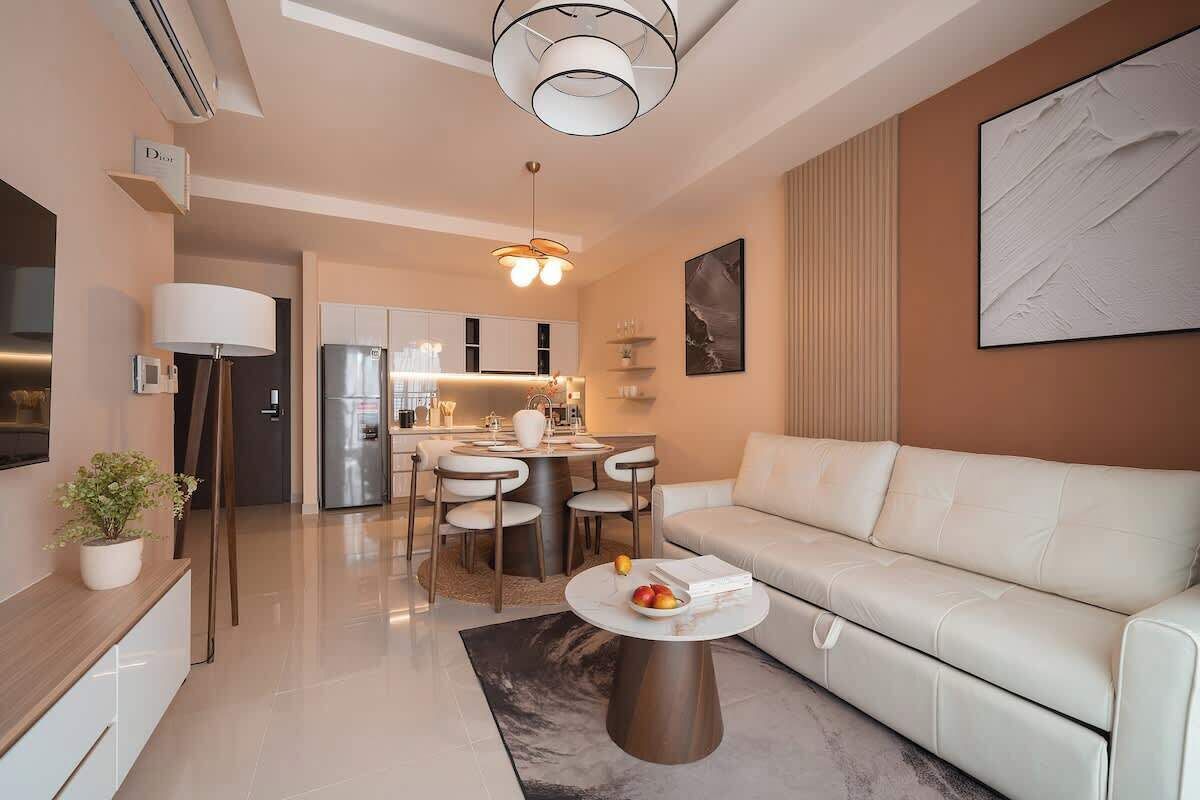 A modern living room with a sofa, a dining area with chairs, a coffee table, and a kitchen in the background.