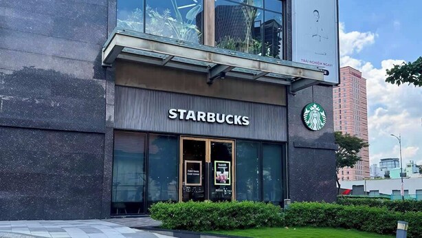 Suuri Starbucks-kyltti, lasinen julkisivu ja rakennuksen heijastus.