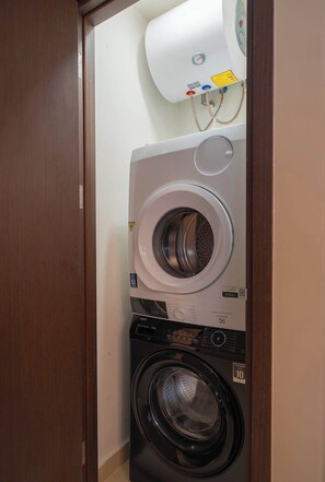 A laundry room with stacked washing machines and a water heater. - 2BR + 2BA • 3 Beds • Group-Friendly • Central • D1 (Ho Chi Minh City)