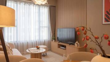Ein modernes Wohnzimmer mit Flachbildfernseher, einer Couch, einem Couchtisch und einem Esstisch mit einem Weinglas.