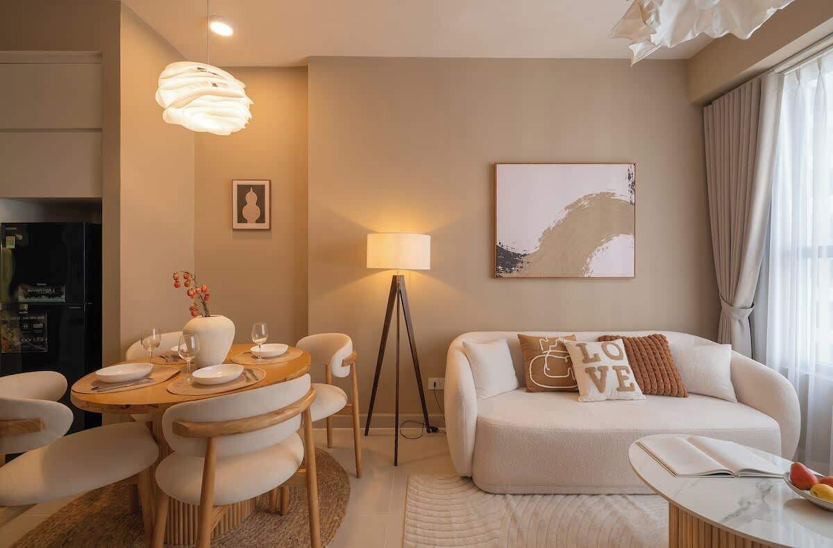 Ein modernes Wohnzimmer mit Essbereich, einer Couch mit Zierkissen, einer Stehlampe und einem Bild an der Wand.