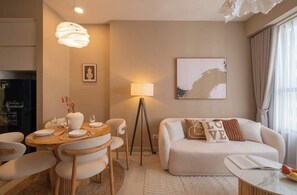 Un salon moderne comprenant un coin repas, un canapé agrémenté de coussins décoratifs, une lampe sur pied et un tableau au mur.