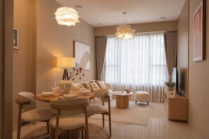 A modern living room with a dining area, a sofa set, a coffee table, and a television on a wooden cabinet. - 2BR + 2BA • 3 Beds • Group-Friendly • Central • D1 (Ho Chi Minh City)