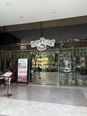 A cafe entrance with a sign reading 'CA PHÊ CÔ BA' and a poster advertising 'Tet At Ty.' - Stunning 3BR+2BA Apt w/View | Near Bui Vien & D1 (Thành phố Hồ Chí Minh)