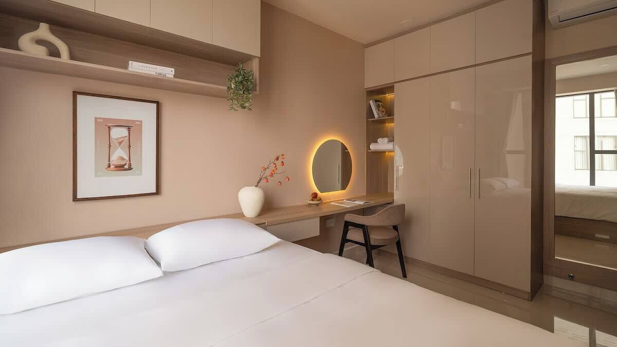 Ein Schlafzimmer mit einem Bett, einem Schreibtisch mit Stuhl, einem Kleiderschrank und einem großen Spiegel.