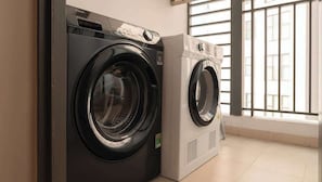 Two front-loading washing machines in a room with a large window. - 4BR · 5 Beds · 2BA · Fireworks/Bitexco View · D4 (Thành phố Hồ Chí Minh)