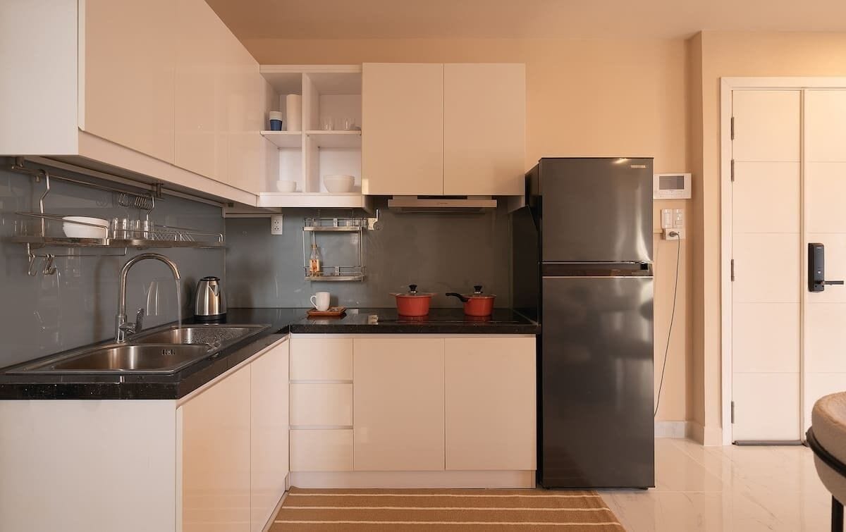 A modern kitchen with a stainless steel refrigerator, a double sink, and white cabinetry.