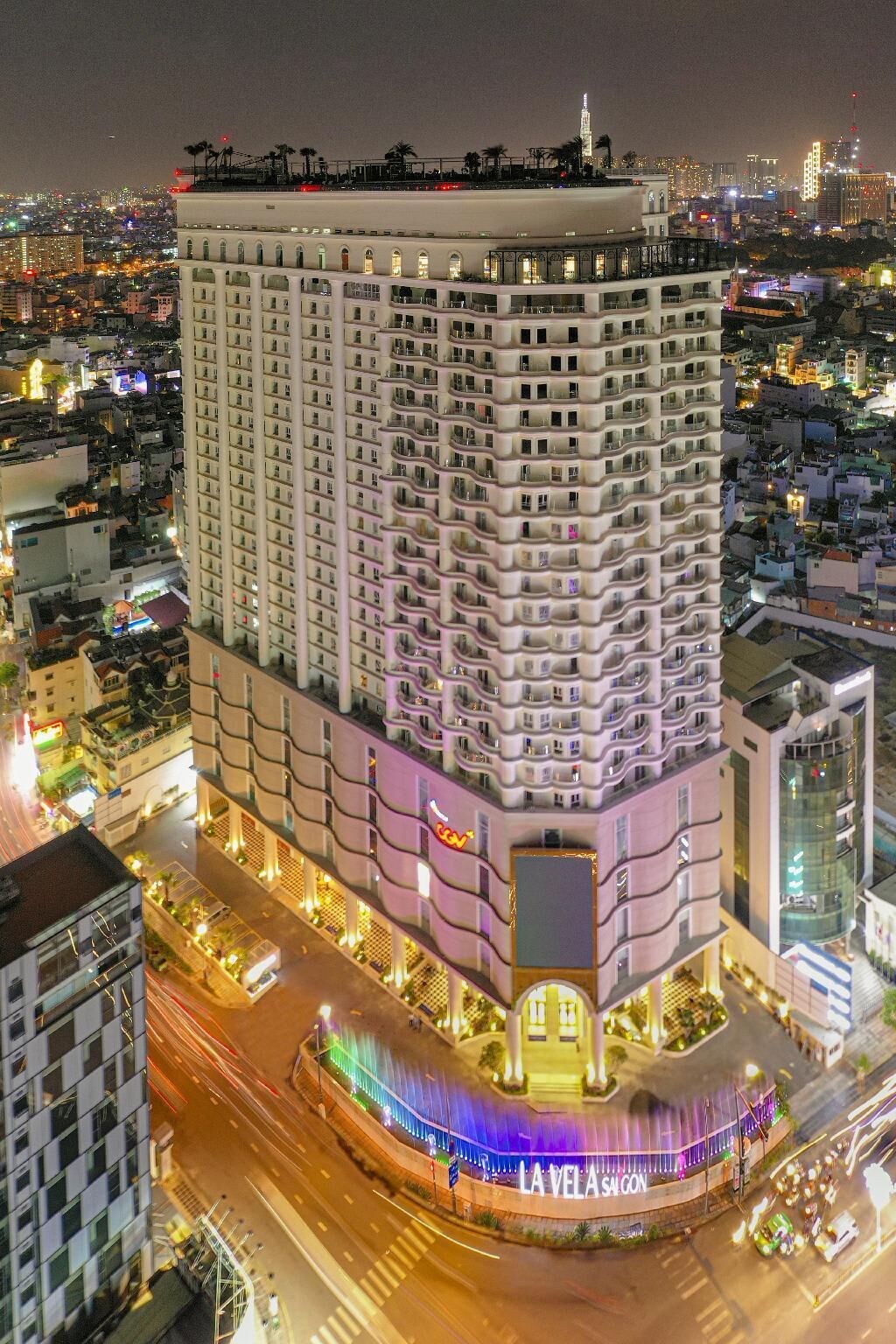 A multi-story hotel with a curved facade, a prominent entrance, and a view of the surrounding cityscape at night.