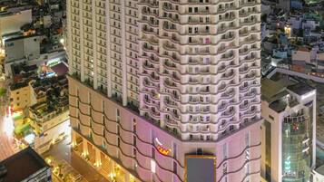 A multi-story hotel with a curved facade, a prominent entrance, and a view of the surrounding cityscape at night.