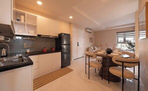 A modern kitchen with white cabinets, a black refrigerator, and a dining area with a round table and chairs. - Warm Central 2BR+1Bath | D3, City View, Pool, Gym (Võ Thị Sáu)