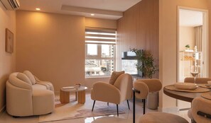 A modern living room with a sofa, armchairs, a coffee table, and a dining area with a table and chairs. - Warm Central 2BR+1Bath | D3, City View, Pool, Gym (Võ Thị Sáu)
