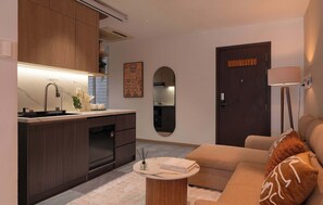 Ein stilvolles Wohnzimmer mit einer Couch, einem Couchtisch und einer Küchenzeile mit Spüle und Schränken.