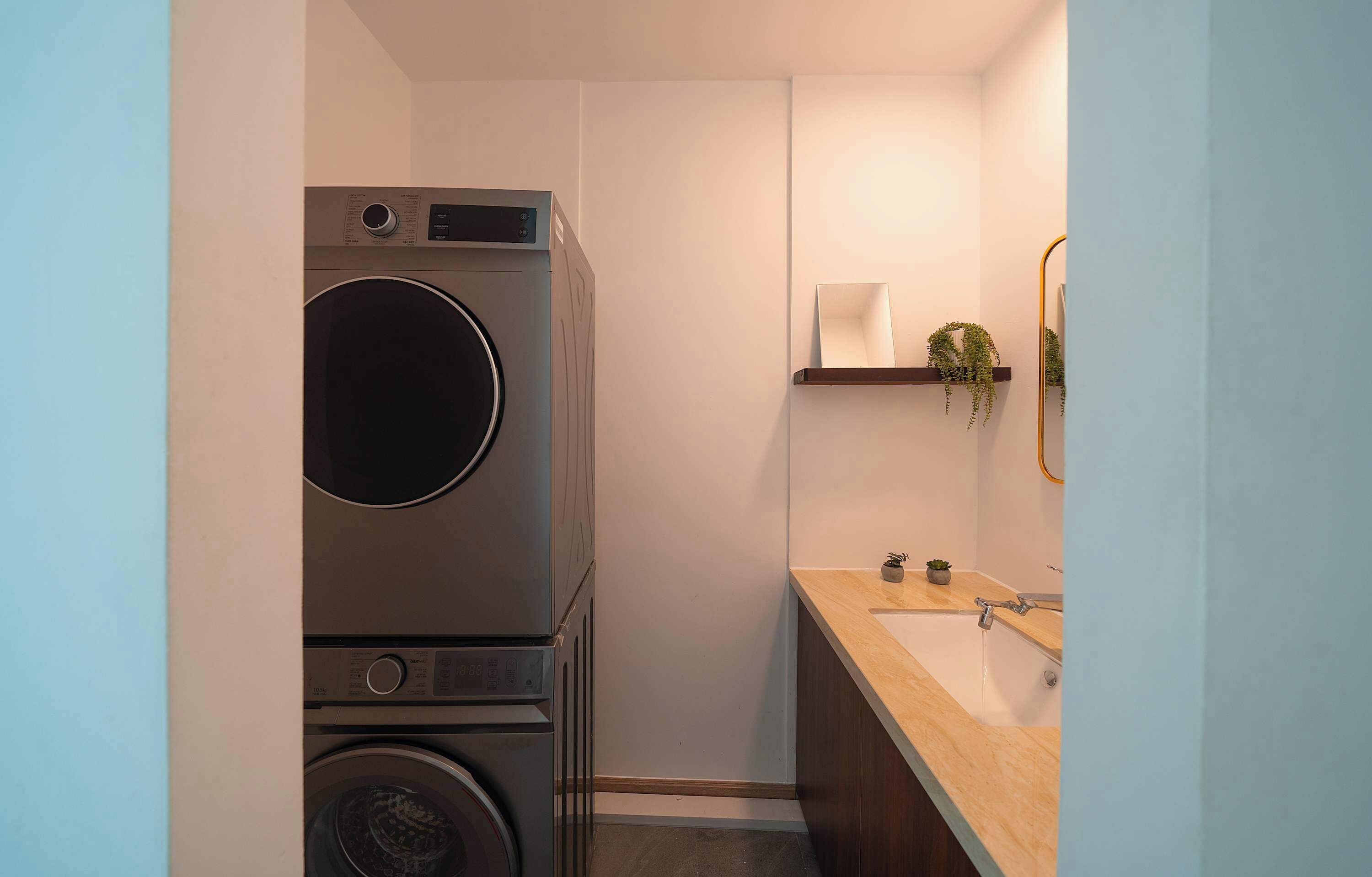 A compact bathroom with a washing machine, a sink, and a mirror.