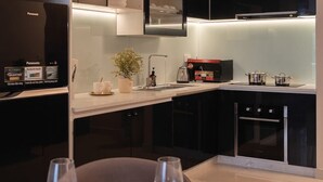 Uma cozinha moderna com armários escuros, forno embutido e área de jantar para quatro pessoas, com mesa e cadeiras.