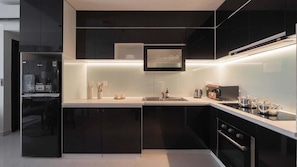 A modern kitchen with black cabinets, a stainless steel sink, and a built-in oven. - Luxe 2BR+1BA | Central, 2 min BuiVien | D1, Tresor (Thành phố Hồ Chí Minh)