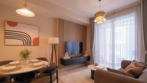 Uma sala de estar moderna com área de jantar, televisão de tela plana e uma grande janela com cortinas.