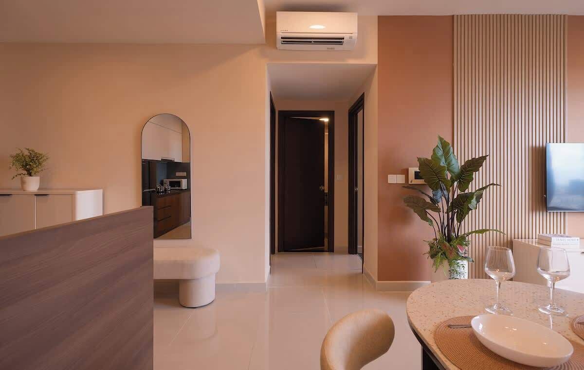 A modern living room with a dining area, a kitchen visible through an archway, and a flat-screen TV mounted on the wall.