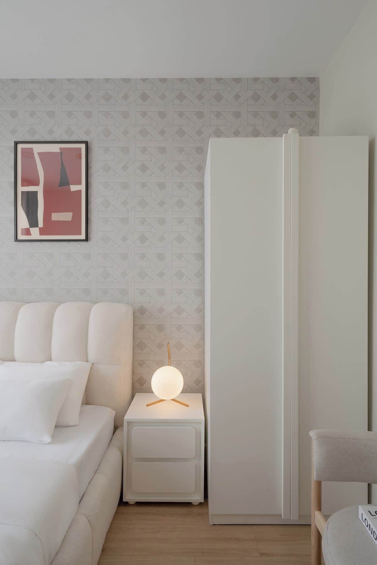 A modern bedroom with a bed, nightstand, and wardrobe.