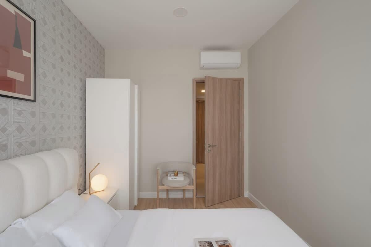 Ein Hotelzimmer mit Bett, Nachttisch, Lampe, Stuhl und einer Tür zu einem Badezimmer.