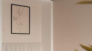 Une chambre à coucher moderne avec un lit blanc, une tête de lit et une œuvre d’art abstraite encadrée accrochée au mur.