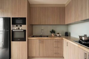A modern kitchen with wooden cabinets, a built-in oven, a microwave, and a sink. - 3BR | 2BA • Near D1 • River View • Dryer • HighFLR (Thành phố Hồ Chí Minh)