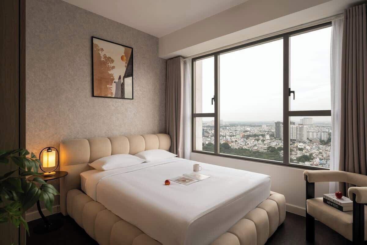 Ein Hotelzimmer mit einem großen Bett, Blick auf die Stadt, einem Nachttisch mit Lampe und einem Sessel.