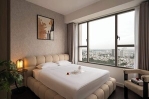 A hotel room with a large bed, a city view, a bedside lamp, a chair, and a framed picture on the wall. - 3BR | 2BA • Near D1 • River View • Dryer • HighFLR (Thành phố Hồ Chí Minh)