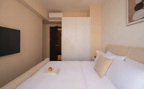 Ein Hotelzimmer mit einem Bett, einem Flachbildfernseher, einem Kleiderschrank und einem Bild an der Wand.