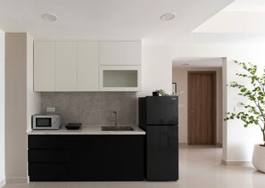 Eine moderne Küche mit weißen Schränken, einem schwarzen Kühlschrank, einer Mikrowelle und einem Spülbecken.