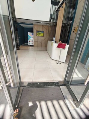 A reception area with a reception desk, a poster on the wall, and a staircase. - 2BR+3 Beds | 1BA • Central D1 • Walk to BuiVien (Thành phố Hồ Chí Minh)