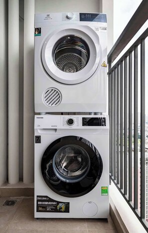 A stacked washer and dryer unit on a balcony with a city view. - 2BR + 3 Beds | 1BA • Central D1 • Side River View (Thành phố Hồ Chí Minh)