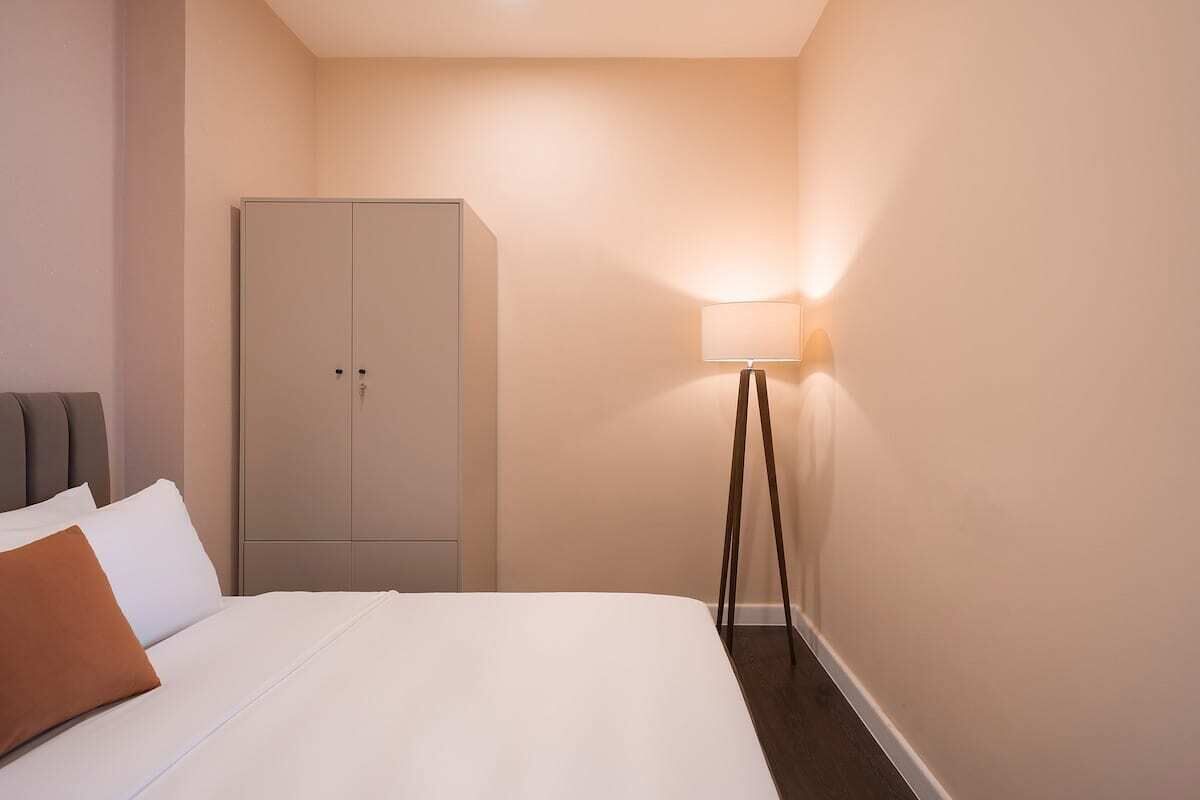 Une chambre d’hôtel avec un lit, une armoire et une lampe sur pied.