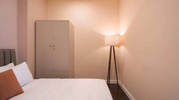 Une chambre d’hôtel avec un lit, une armoire et une lampe sur pied.