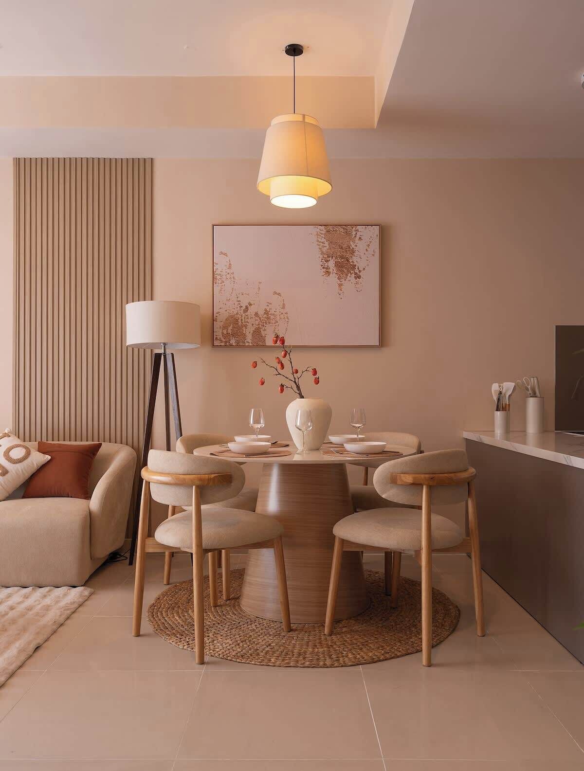 Un comedor moderno con una mesa redonda, sillas y una lámpara colgante.