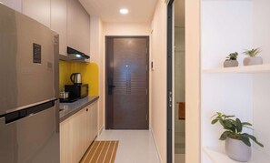 Una cocina compacta con refrigerador, microondas y hervidor sobre la encimera.