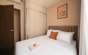 Ein Hotelzimmer mit Bett, geschlossener Tür und einem an der Wand hängenden Bild.