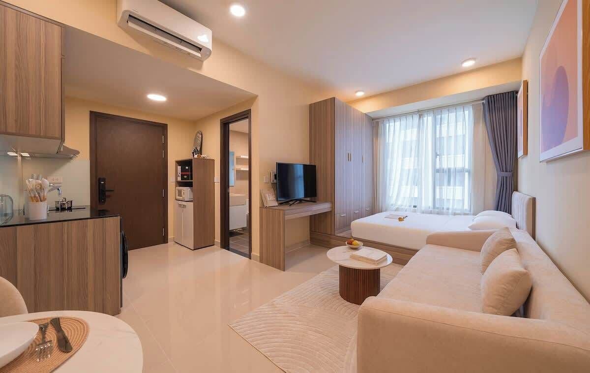 Ein modernes Wohnzimmer mit einer Couch, einem Couchtisch, einem Fernseher und einer Küchenzeile mit Schränken und einer Mikrowelle.
