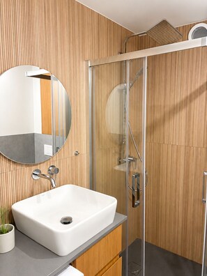 A modern bathroom with a white sink, a round mirror, and a glass shower enclosure. - Native Apartments Starowiślna 25 (Kraków)