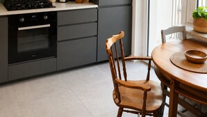 Ett modernt kök med en gasspis, ugn och en matplats med ett bord och stolar i trä.