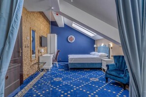 A bedroom with a sloped ceiling, a bed, a desk, a chair, and a patterned carpet. - Czeczotka Palace Apartments Old Town (Kraków)