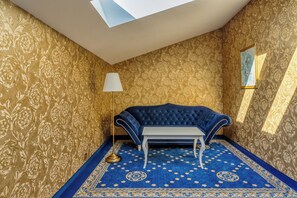 A room with a blue sofa, a small table, patterned carpet, and ornate wallpaper. - Czeczotka Palace Apartments Old Town (Kraków)