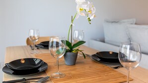 A dining table set with black plates, wine glasses, and a potted orchid. - Platinum Breeze - 1-BR Apt. in Larnaca (Larnaka)