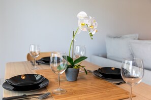 A dining table set with black plates, wine glasses, and a potted orchid. - Platinum Breeze - 1-BR Apt. in Larnaca (Larnaka)